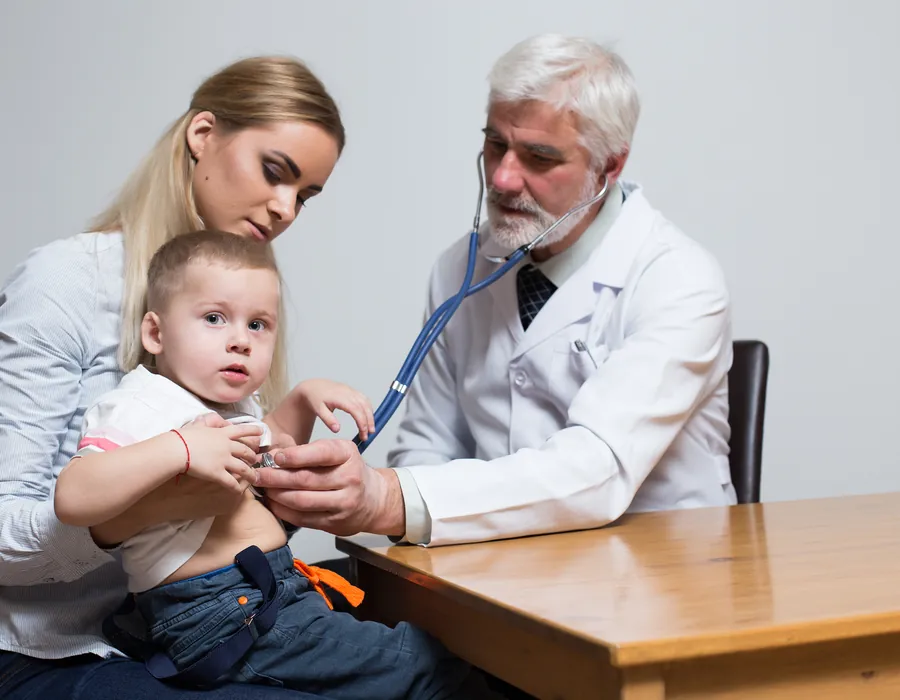 Doctor examining a young child with a parent during a consultation