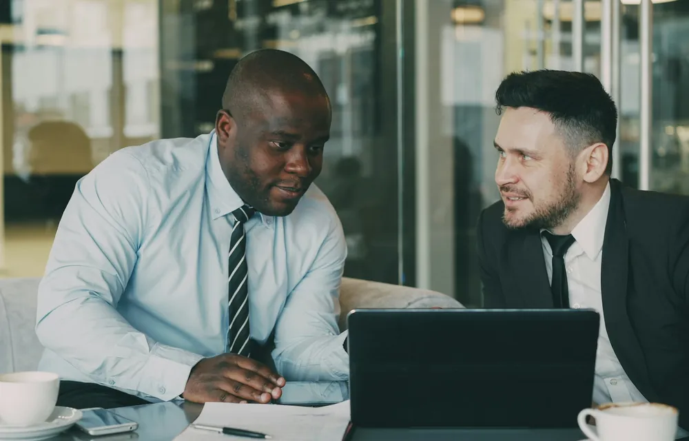 Two business partners discussing an agreement over a laptop